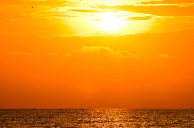 deniz üzerinde bulutlu turuncu günbatımı