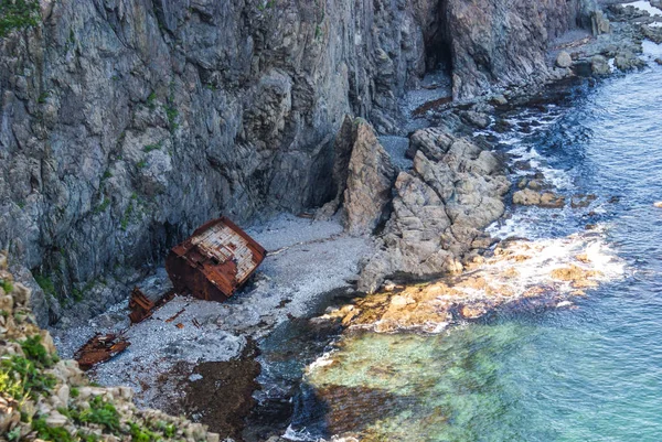 Un viejo barco naufragado se encuentra en la orilla al pie de un roc — Foto de Stock