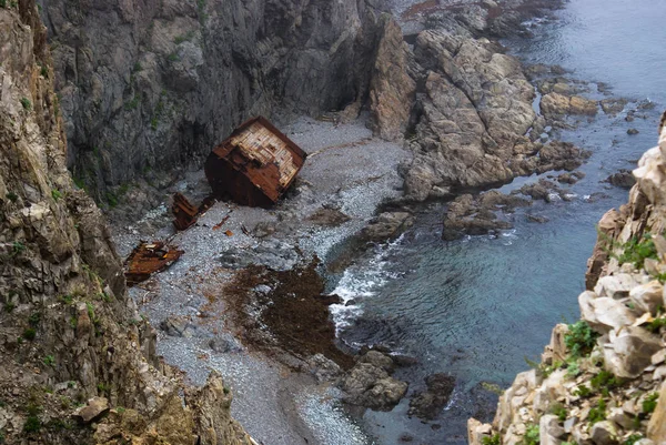 Una vecchia nave naufragata si trova sulla riva ai piedi di un roc — Foto Stock
