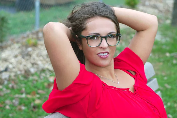公園に座っている若い女性赤いドレスの女性 — ストック写真