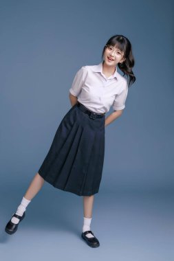 Klasik okul üniformalı ve gözlüklü Asyalı öğrenci bir tablet, modern sınıfta teknoloji, yaratıcı düşünce ve sınav hazırlığı, eğitim promosyonları tutuyor..