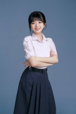 Klasik okul üniformalı ve gözlüklü Asyalı öğrenci bir tablet, modern sınıfta teknoloji, yaratıcı düşünce ve sınav hazırlığı, eğitim promosyonları tutuyor..