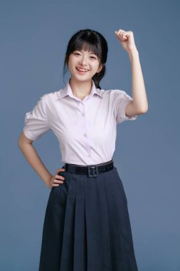 Klasik okul üniformalı ve gözlüklü Asyalı öğrenci bir tablet, modern sınıfta teknoloji, yaratıcı düşünce ve sınav hazırlığı, eğitim promosyonları tutuyor..