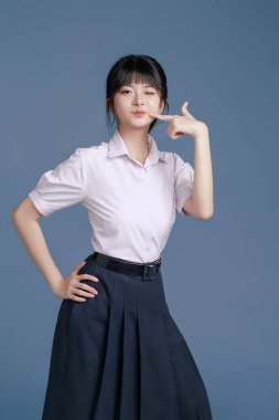 Klasik okul üniformalı ve gözlüklü Asyalı öğrenci bir tablet, modern sınıfta teknoloji, yaratıcı düşünce ve sınav hazırlığı, eğitim promosyonları tutuyor..