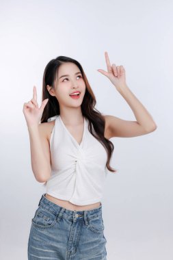 Boş fotokopi alanını gösteren mutlu genç Asyalı kadın. Reklamınız, terfiniz ya da pazarlama mesajınız için mükemmel. Temiz beyaz arka planda neşeli bir model, mesajınız için hazır..