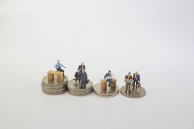 Sikke yığını üzerinde ayakta küçük iş figürü