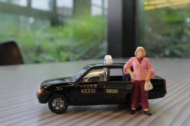 küçük insan figürü ve bir taksi