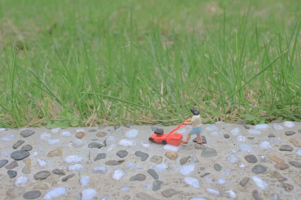 Mini figura usando empurrar cortador de grama cortador de grama jarda — Fotografia de Stock