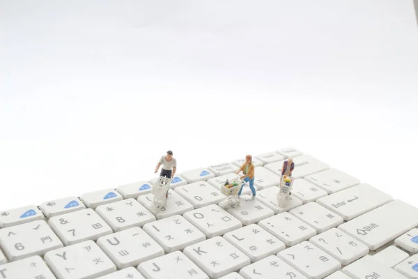 tiny figure shoppers with shopping cart on a computer keyboard