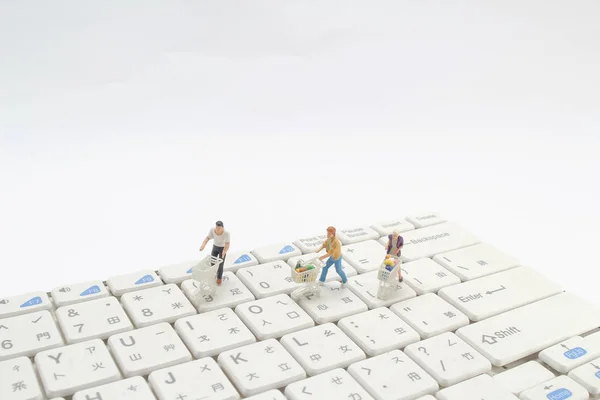 tiny figure shoppers with shopping cart on a computer keyboard