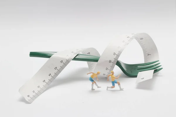 Figurine de mini coureur avec ruban à mesurer enroulé autour d'une fourchette lyi — Photo