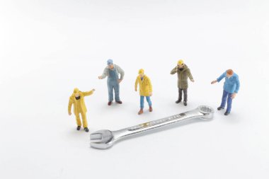 Bir cıvata somununu sıkıştıran küçük bir oyuncak işçisi 