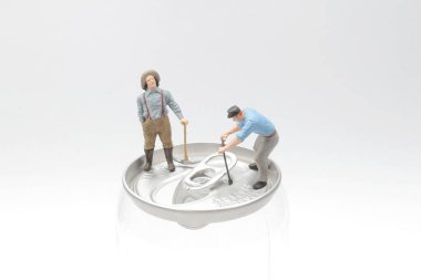 İşçi adam konserve açıyor. Mini işçiler sodanın üstünde 