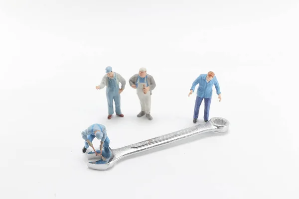 A tiny toy workers tightening a nut of a bolt — Stock Photo, Image