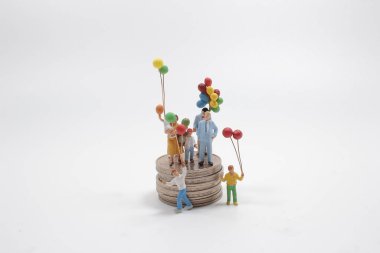Balonlu mini figürlü aile bozuk para yığınının üstünde duruyor..