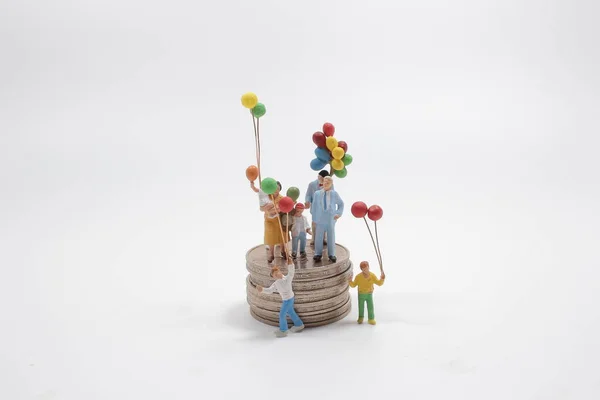 mini figure family with balloon standing on stack of coins.