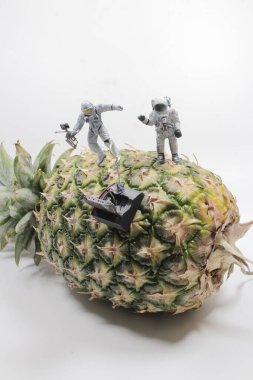 Beyaz takım elbiseli astronot ananasın etrafında uçuyordu.