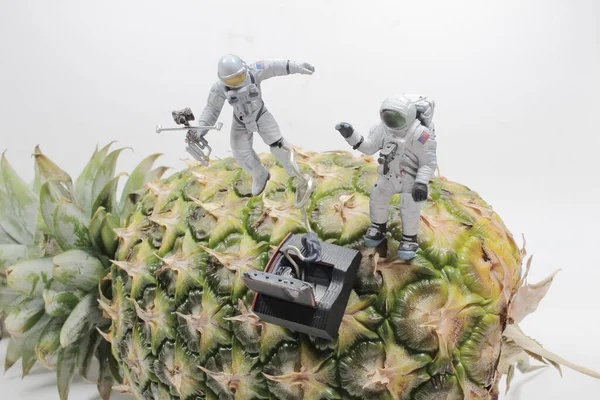 Astronaut in an white suit fly arounbd the pineapple