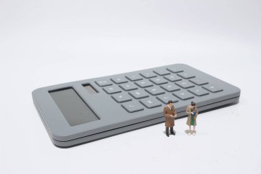 Elinde hesap makinesi olan küçük bir iş adamı. 