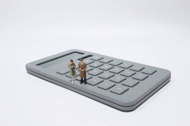 Elinde hesap makinesi olan küçük bir iş adamı. 