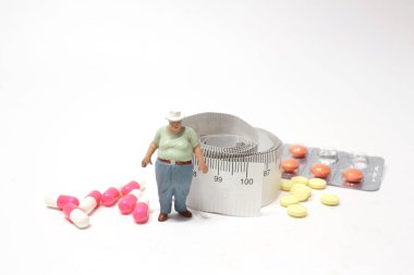 Şişman, şişman, haplı ve mezuralı bir adam figürü.