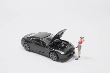 Mini figür tamirci tozlu araba tekerleğini tamir ediyor.,