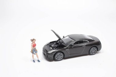 Mini figür tamirci tozlu araba tekerleğini tamir ediyor.,