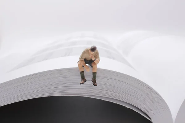 a mini people sitting on book, using as education