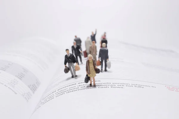 a mini people figure travel on open pages