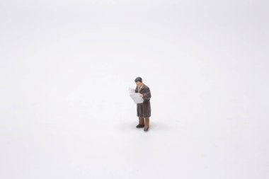 Mini işadamı nesne üzerine gazete okuyor.