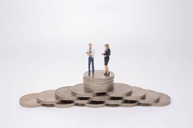 Mini model figürleri madeni para yığınları üzerinde karar veriyor