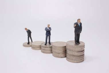 Para yığınının üzerinde duran küçük bir figür. Para ve finansal kavramlar.