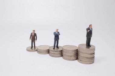 Para yığınının üzerinde duran küçük bir figür. Para ve finansal kavramlar.