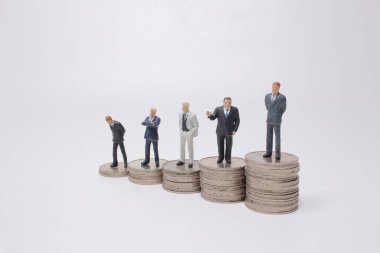 Para yığınının üzerinde duran küçük bir figür. Para ve finansal kavramlar.