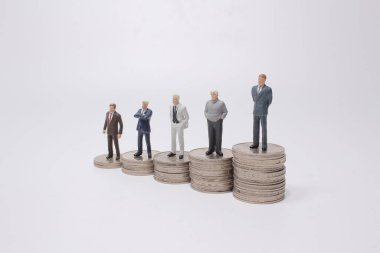 Para yığınının üzerinde duran küçük bir figür. Para ve finansal kavramlar.