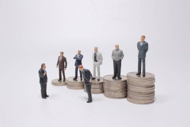 Para yığınının üzerinde duran küçük bir figür. Para ve finansal kavramlar.