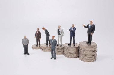 Para yığınının üzerinde duran küçük bir figür. Para ve finansal kavramlar.