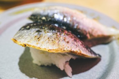 Lezzetli ızgara uskumru suşisi beyaz tabağa güzelce yerleştirilmiş.