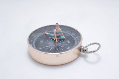 Pusula üzerinde yoga yapan küçük bir figürün yaratıcı tasviri.,