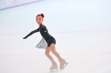 Zarif genç kız buzda kayıyor, göz kamaştırıcı bir figür sergiliyor.