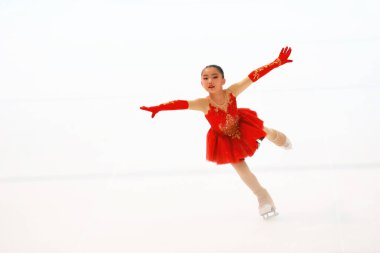 Zarif genç kız buzda kayıyor, göz kamaştırıcı bir figür sergiliyor.