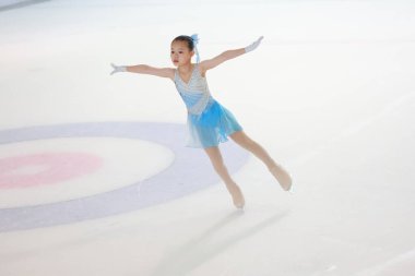 Genç kız buz üzerinde kayıyor, çarpıcı ve zarif bir figür sergiliyor.
