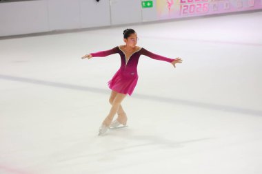 Genç, zarif kız muhteşem bir artistik patinaj pozu veriyor.