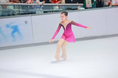 Zarif genç kız buzda kayıyor, göz kamaştırıcı bir figür sergiliyor.