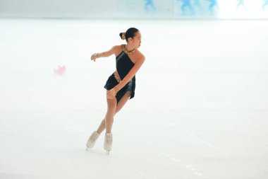 Mavi elbiseli yetenekli artistik patinajcı zarif bir şekilde karmaşık bir duruş sergiliyor.