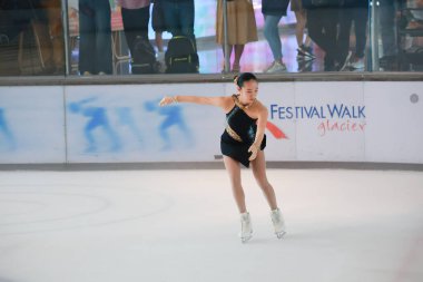 Mavi elbiseli yetenekli artistik patinajcı zarif bir şekilde karmaşık bir duruş sergiliyor.