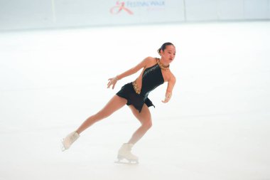 Mavi elbiseli yetenekli artistik patinajcı zarif bir şekilde karmaşık bir duruş sergiliyor.