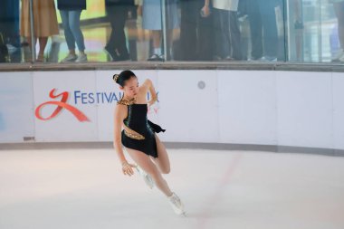 Mavi elbiseli yetenekli artistik patinajcı zarif bir şekilde karmaşık bir duruş sergiliyor.