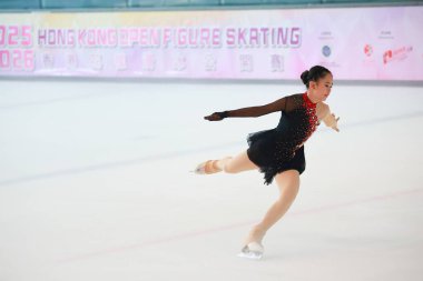 Mavi elbiseli yetenekli artistik patinajcı zarif bir şekilde karmaşık bir duruş sergiliyor.