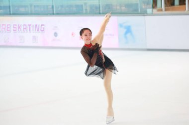 Mavi elbiseli yetenekli artistik patinajcı zarif bir şekilde karmaşık bir duruş sergiliyor.